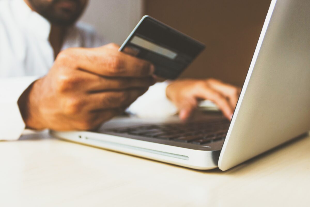 Person sitting at a laptop with a credit card in hand